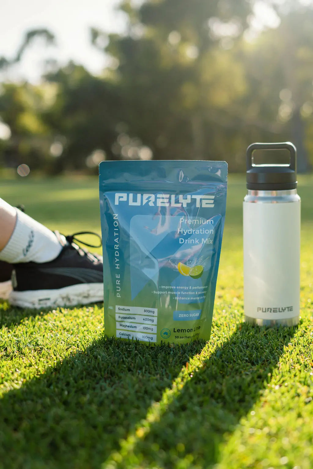 Purelyte Hydration Starter Pack - PURELYTE Lemon Lime electrolyte pack and white water bottle on a grassy field