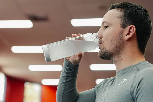 Man drinking electrolytes after exercise to rehydrate following sweat loss.